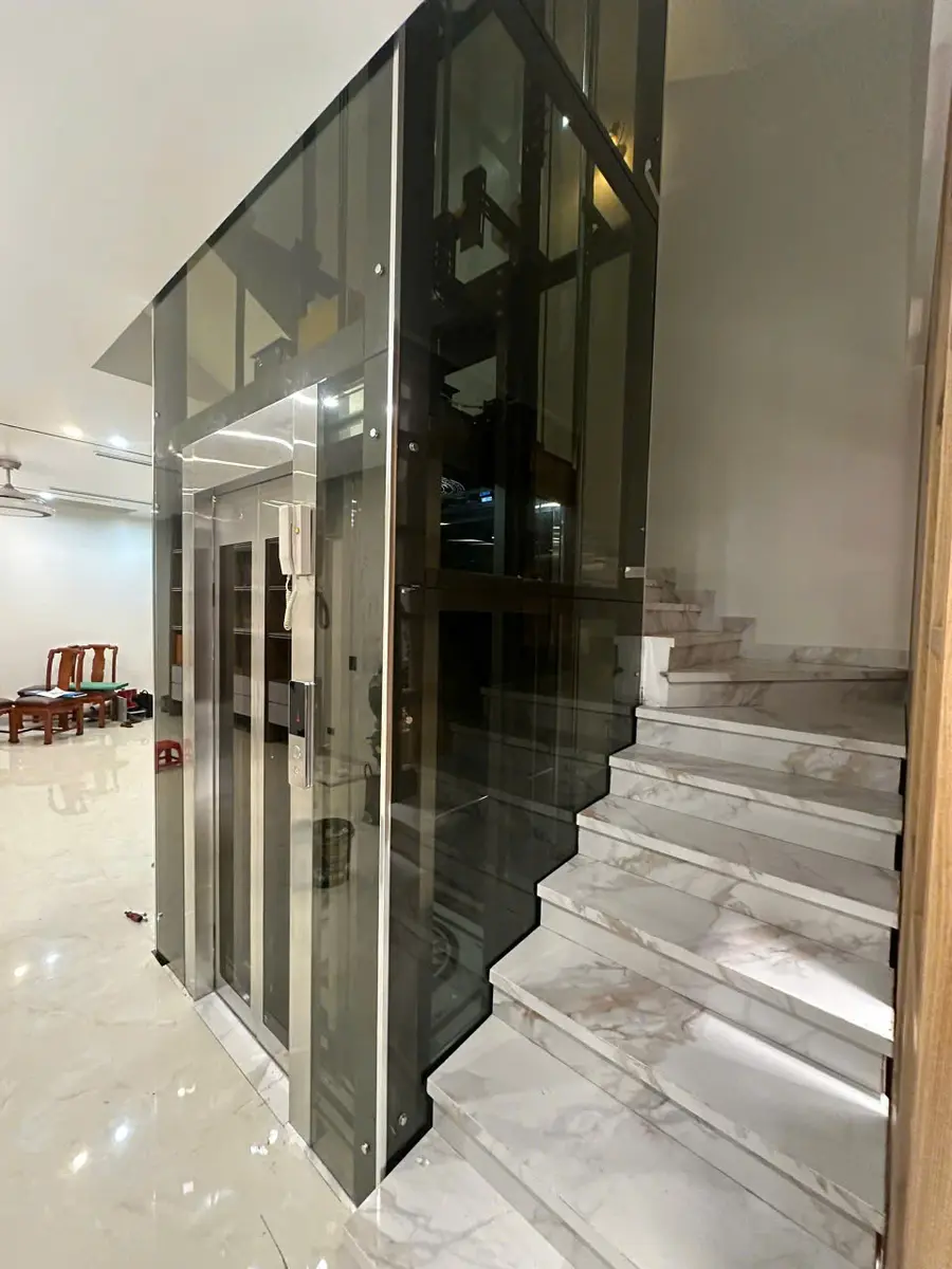 Thang máy cáp kéo giếng kính cạnh cầu thang